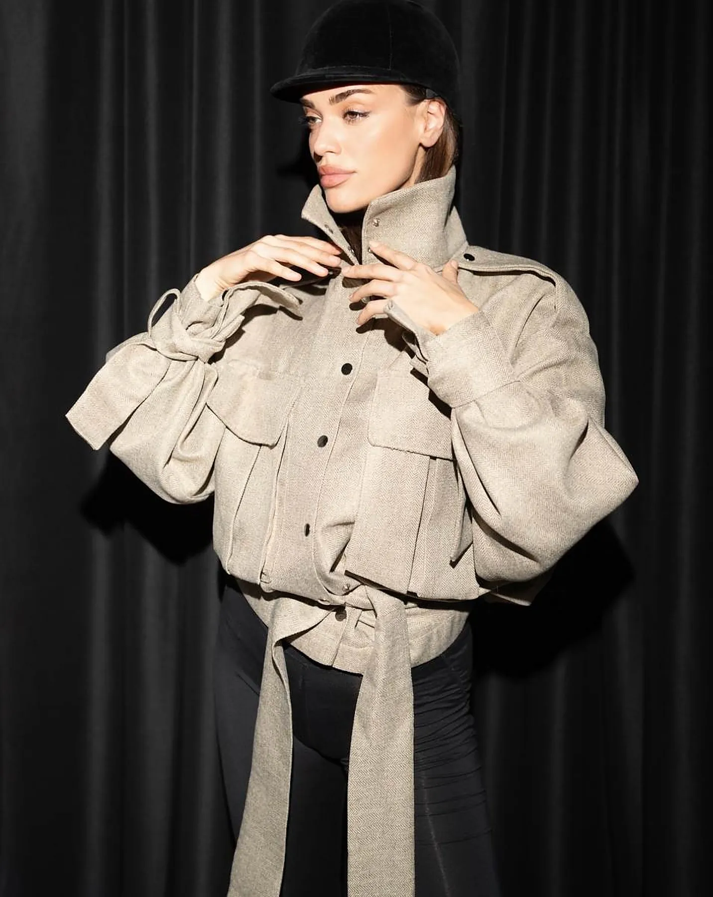 Model in a beige utility jacket adjusting the high collar
