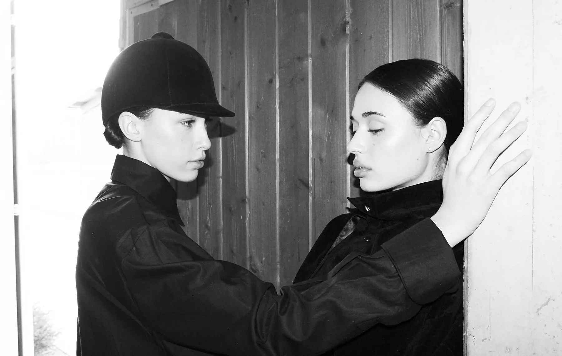 Black and white portrait of two models in black riding jackets and caps