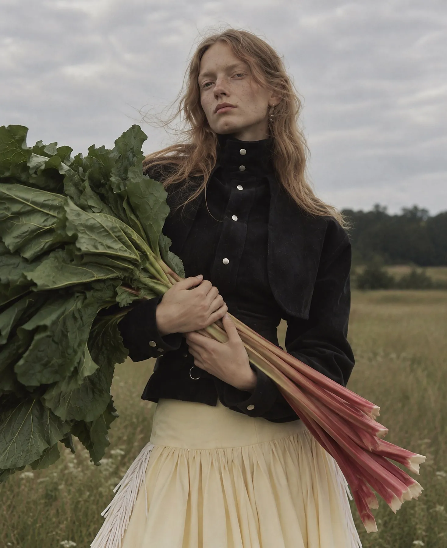 Close portrait of a model in a black snap-button jacket holding rhubarb